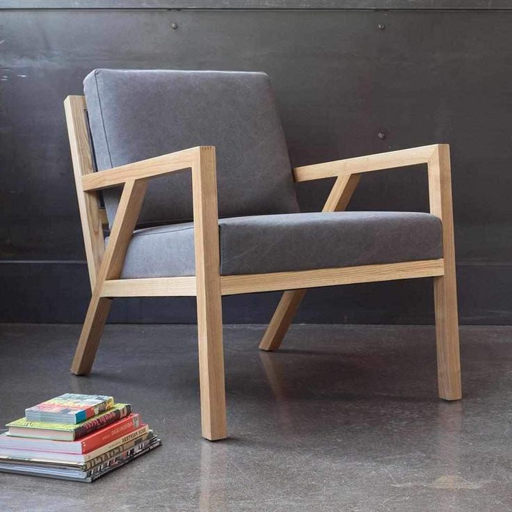 a wooden chair sitting next to a stack of books on the floor in front of a gray wall