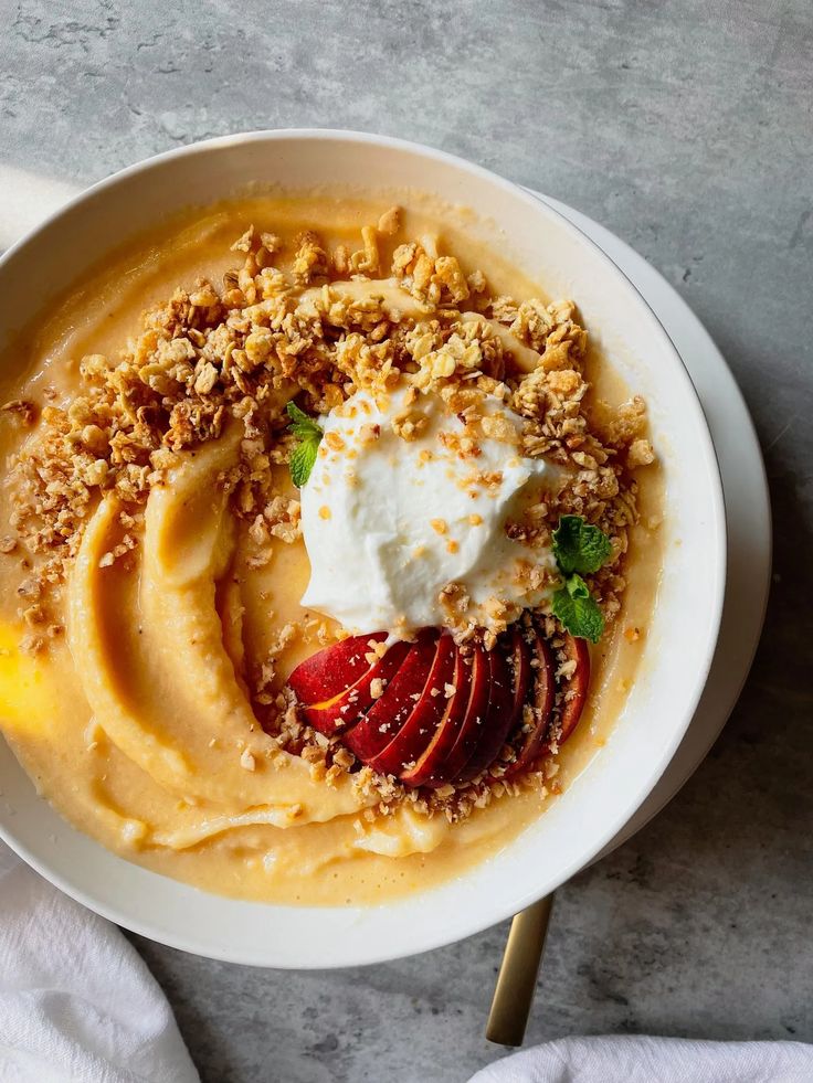 a white bowl filled with food on top of a table next to a napkin and fork