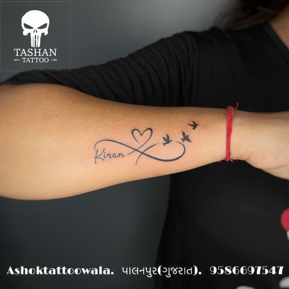 a woman with a tattoo on her arm that says love and two birds in the shape of a heart