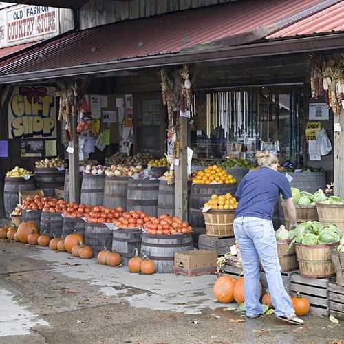 a man standing in front of a store filled with lots of fruits and veggies