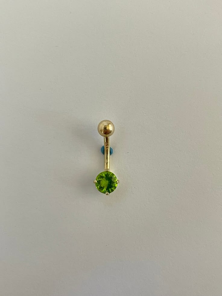 a single green jewel sits on a white surface