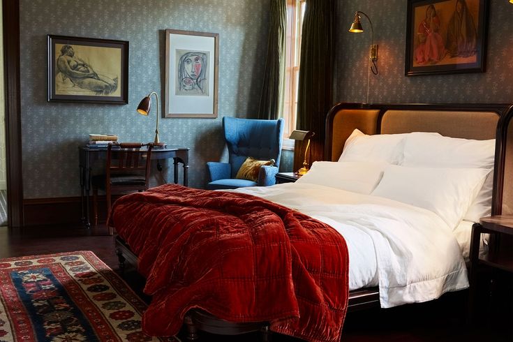 a large bed in a bedroom next to a painting on the wall and a chair