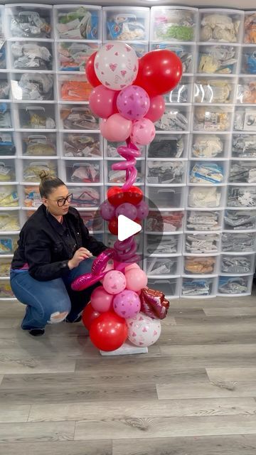 a woman kneeling down next to a bunch of balloons