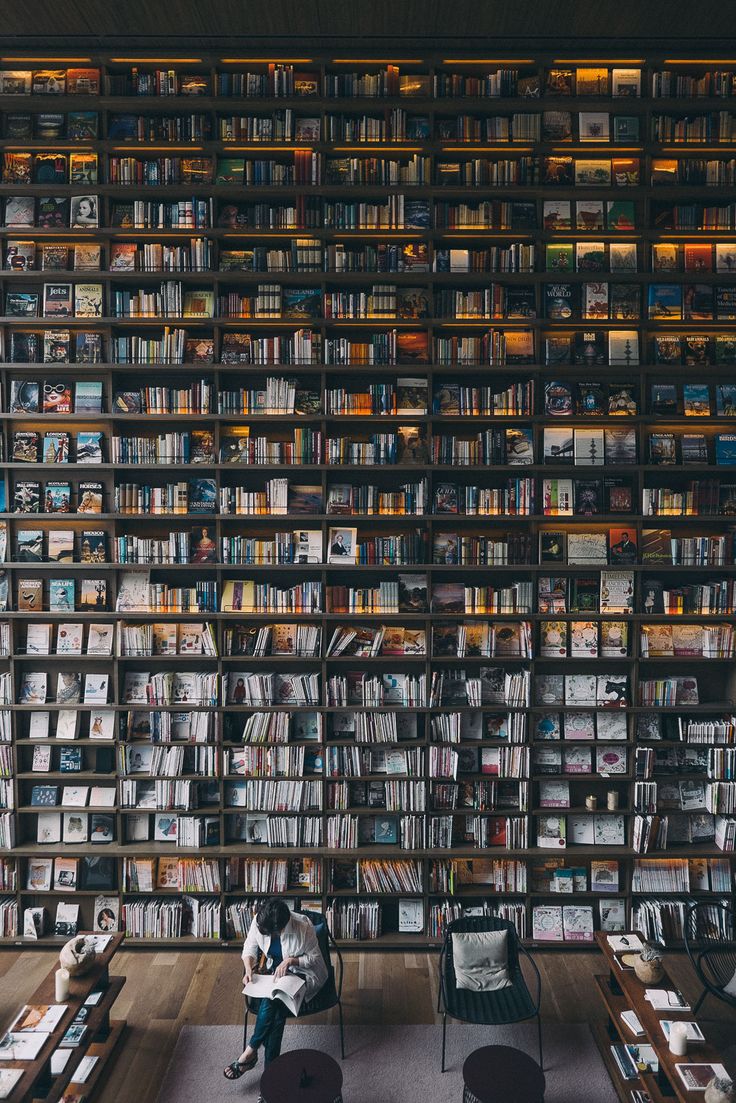 a man sitting in front of a bookshelf filled with lots of books on it