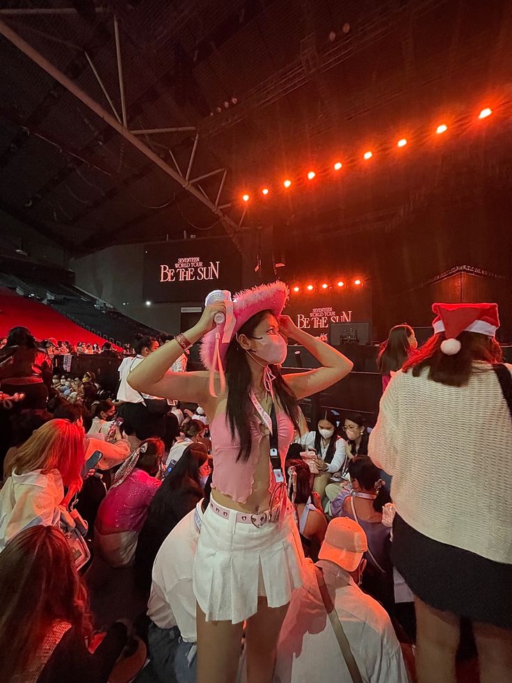 a woman wearing a pink hat standing in front of a crowd