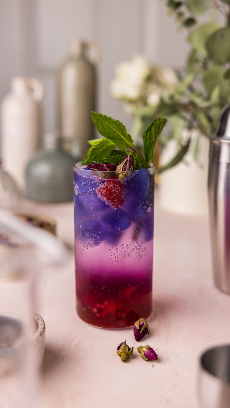 a drink with berries and mint sitting on a table