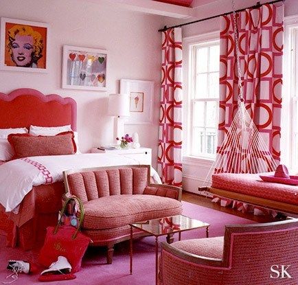 a bedroom decorated in pink and red with pictures on the wall