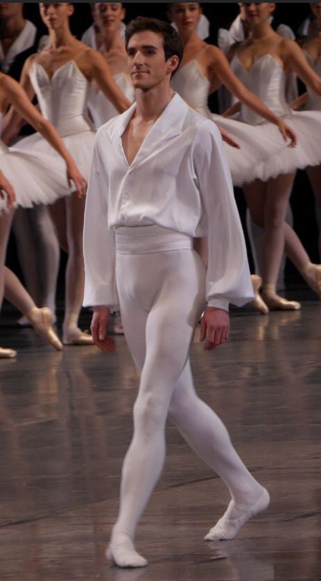 a man in white is walking on the dance floor with other dancers behind him,