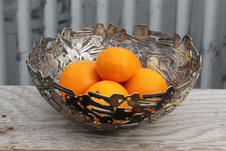 a glass bowl filled with oranges on top of a wooden table