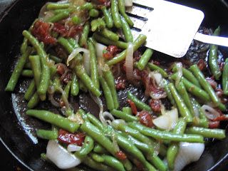 green beans and onions are being cooked in a skillet with a white spatula