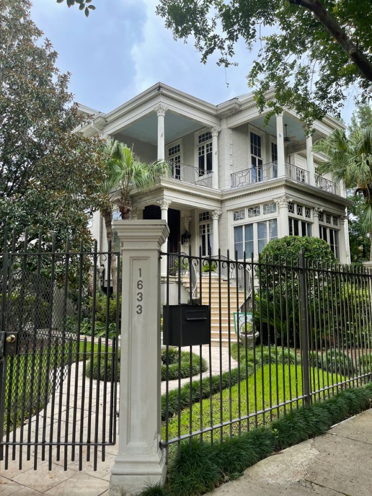 a large white house behind a black fence