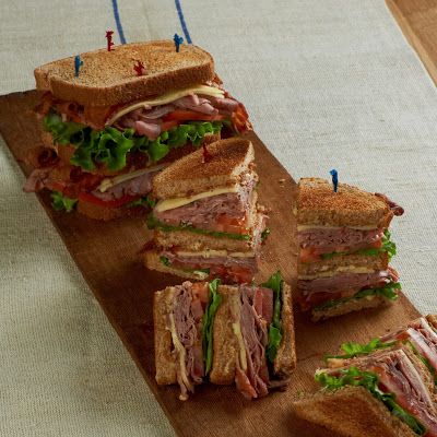 a wooden cutting board topped with cut in half sandwiches