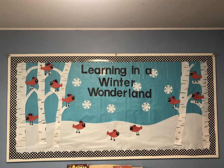 a bulletin board with trees and birds on it in the middle of a classroom room