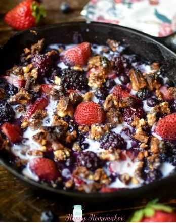 berries and granola in a cast iron skillet with yogurt on top