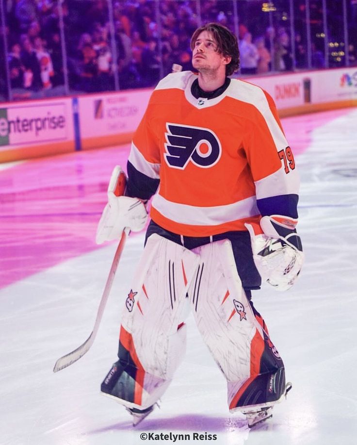 a hockey player standing on the ice in front of an arena with people watching him