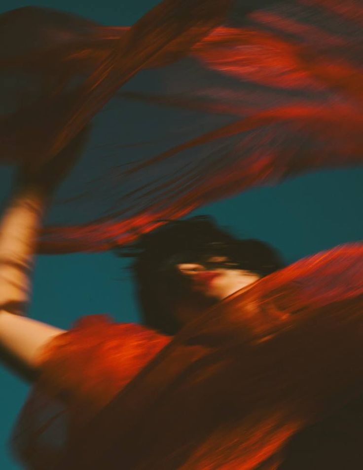 a woman with her hair blowing in the wind, looking up at something blue and red