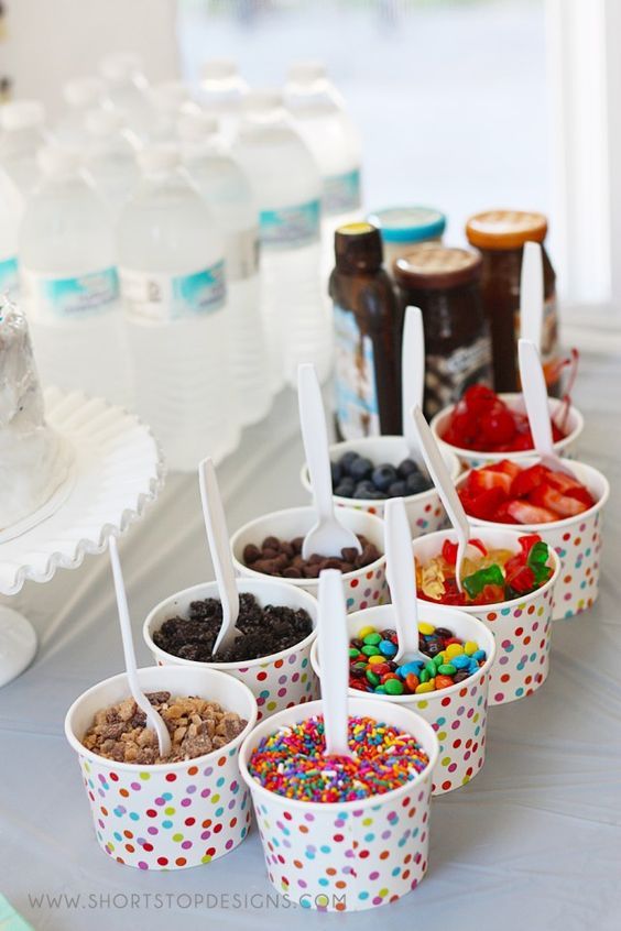 several cups filled with different kinds of candy and toppings on top of a table