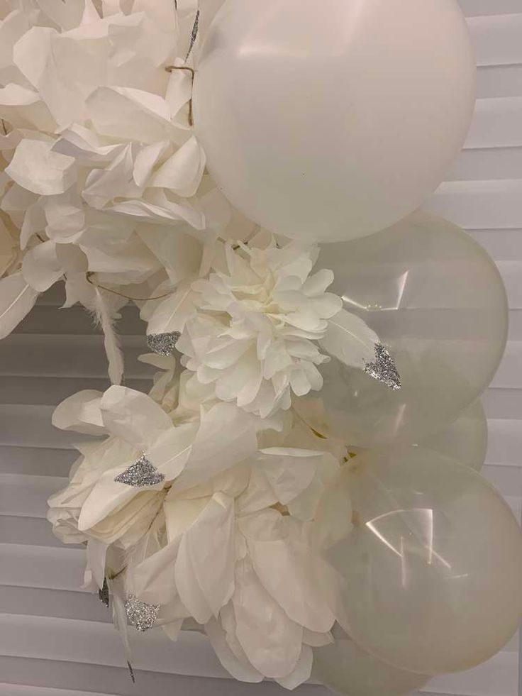 white flowers and balloons are hanging from the ceiling