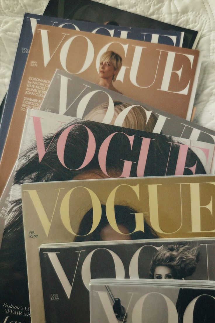 several magazines stacked on top of each other in front of a white bed coverlet