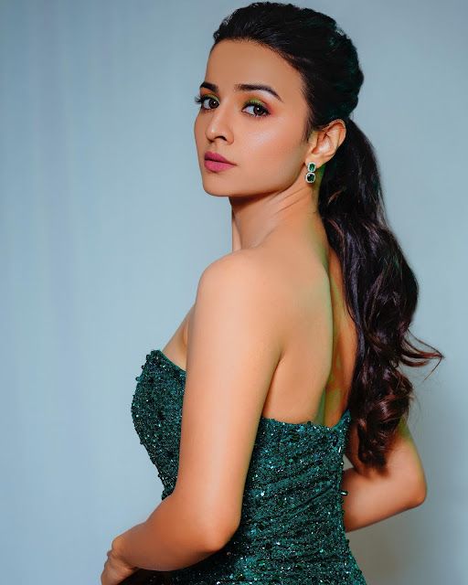 a beautiful young woman in a green dress posing for the camera with her hand on her hip