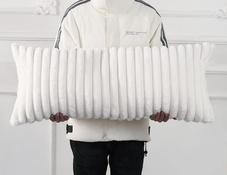 a person holding a large pile of white pillows in front of their face and arms