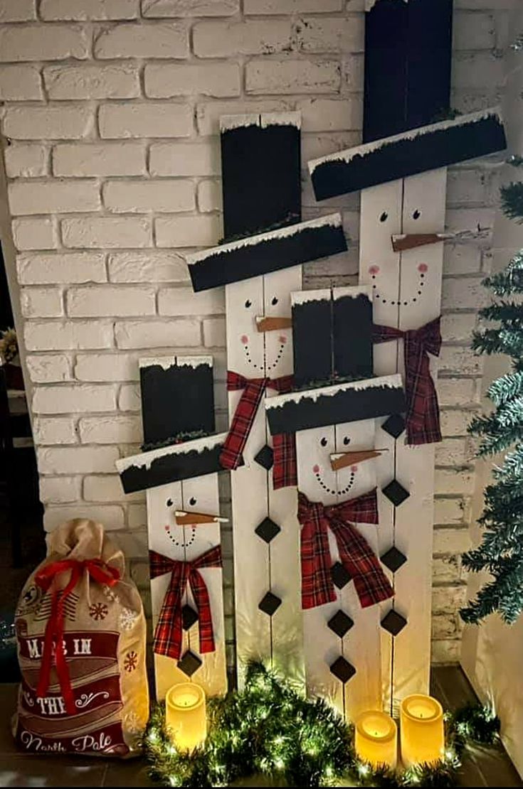 snowmen made out of wooden boards with candles on the side and christmas decorations around them