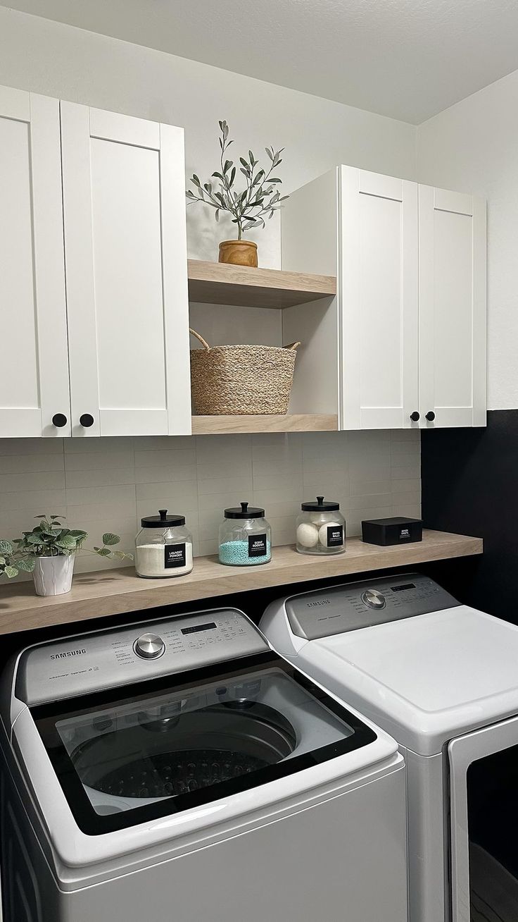 a washer and dryer in a laundry room with white cabinets on the wall