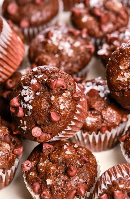 chocolate muffins with sprinkles and powdered sugar are piled on top of each other