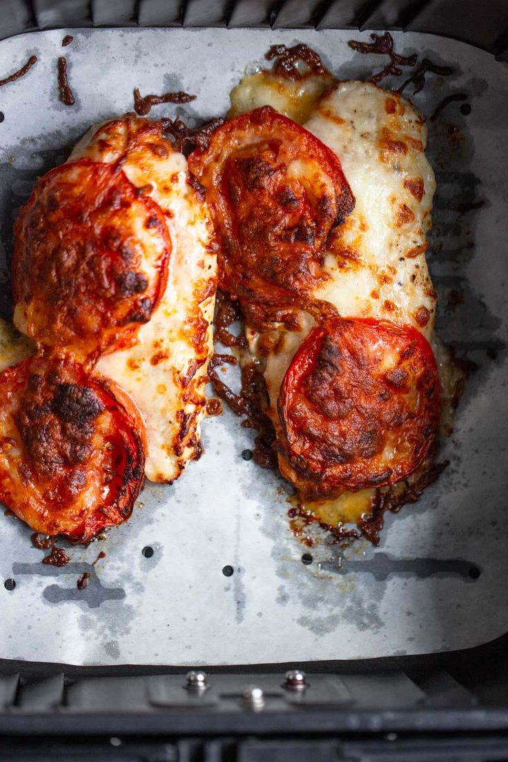 two pieces of pizza sitting on top of an oven pan covered in cheese and tomato sauce