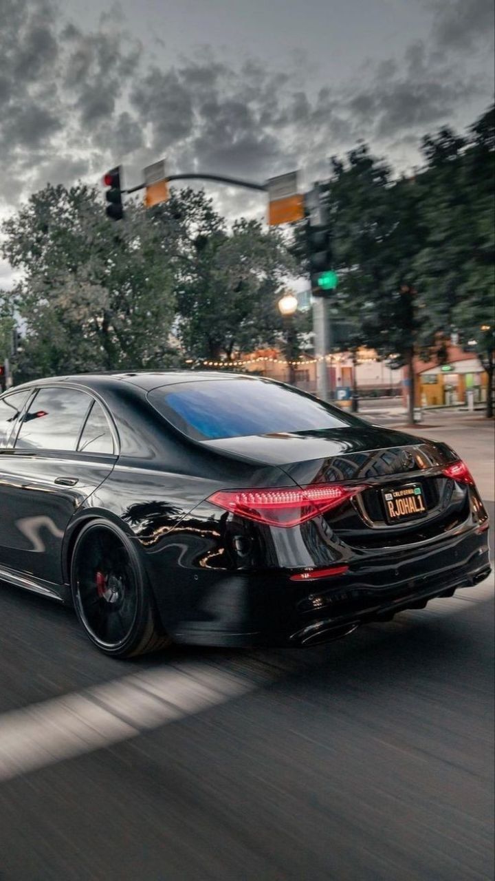 a black car is driving down the street