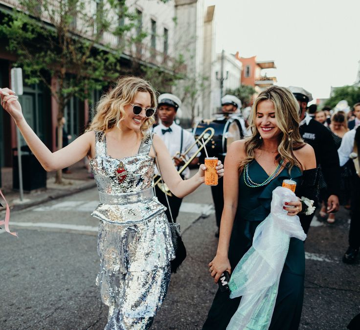 two women walking down the street holding onto some pink streamers in their hands and smiling