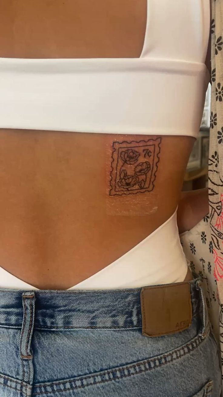 the back of a woman's stomach with a small tattoo on her left side