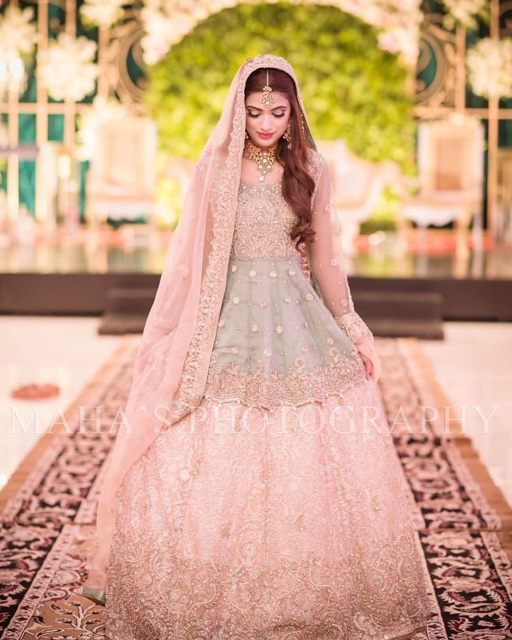 a woman in a wedding dress and veil standing on a rug with an ornate archway behind her