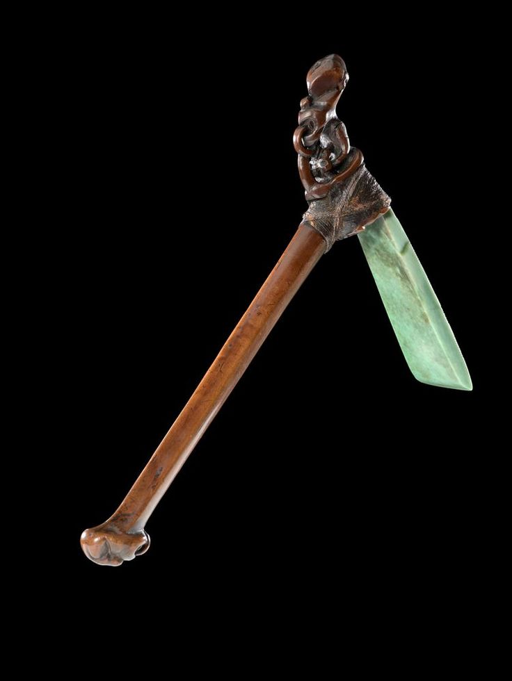 an old metal and wood object with a green blade on it's tip, against a black background