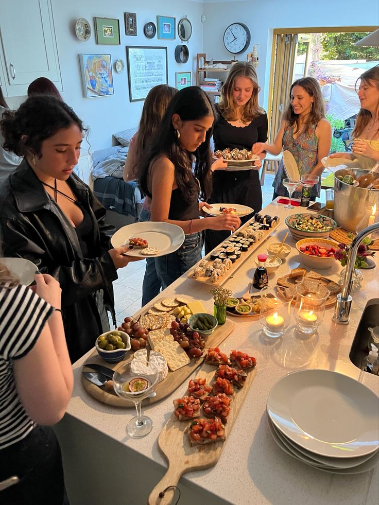 a group of women standing around a table with plates and bowls of food on it