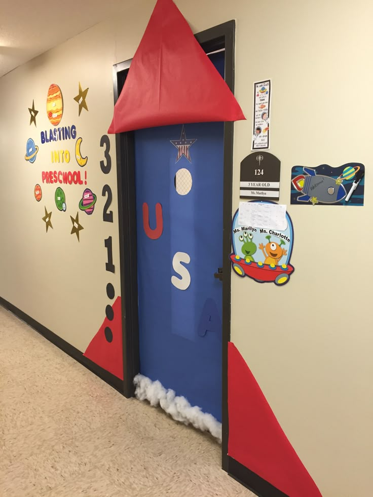 a classroom door decorated in the shape of a rocket ship with a red hat on top