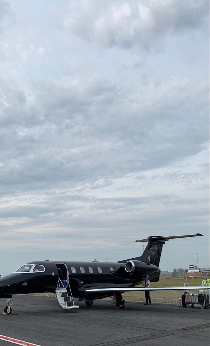 an airplane is parked on the tarmac with people standing around it and another plane in the background