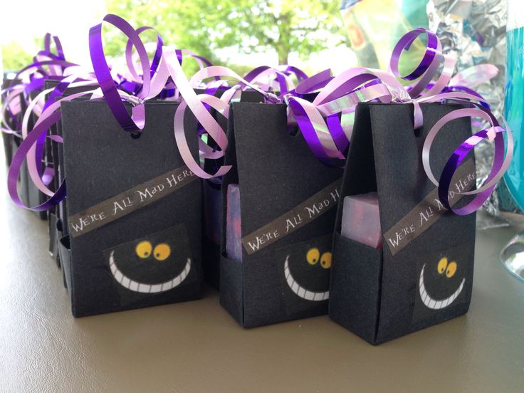 three black bags decorated with purple ribbons and eyes are sitting next to each other on a table