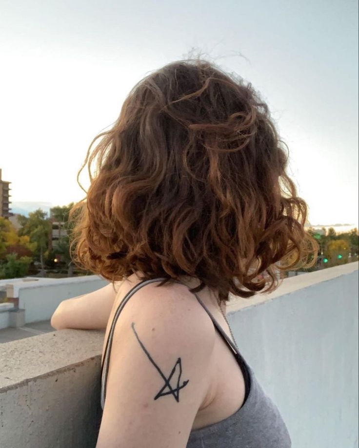 the back of a woman's shoulder with an arrow tattoo on her left arm