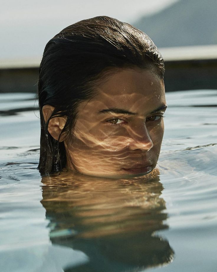 a woman is floating in the water with her head above the water's surface