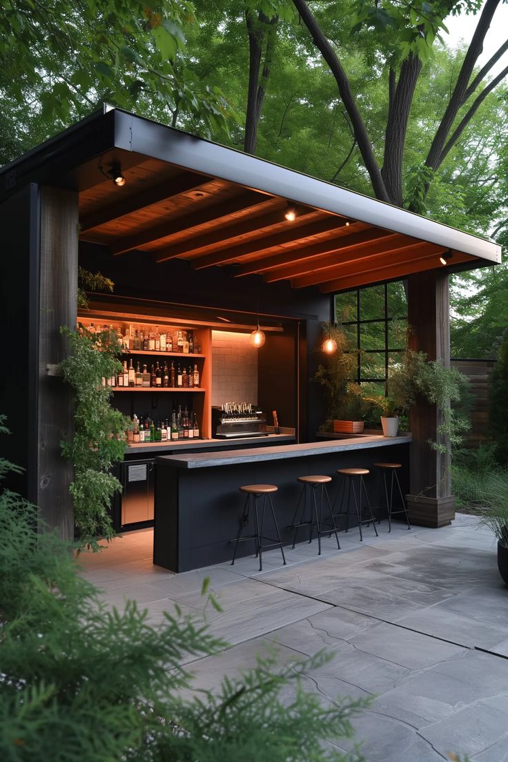 an outdoor bar with stools under a canopy in the middle of a garden area