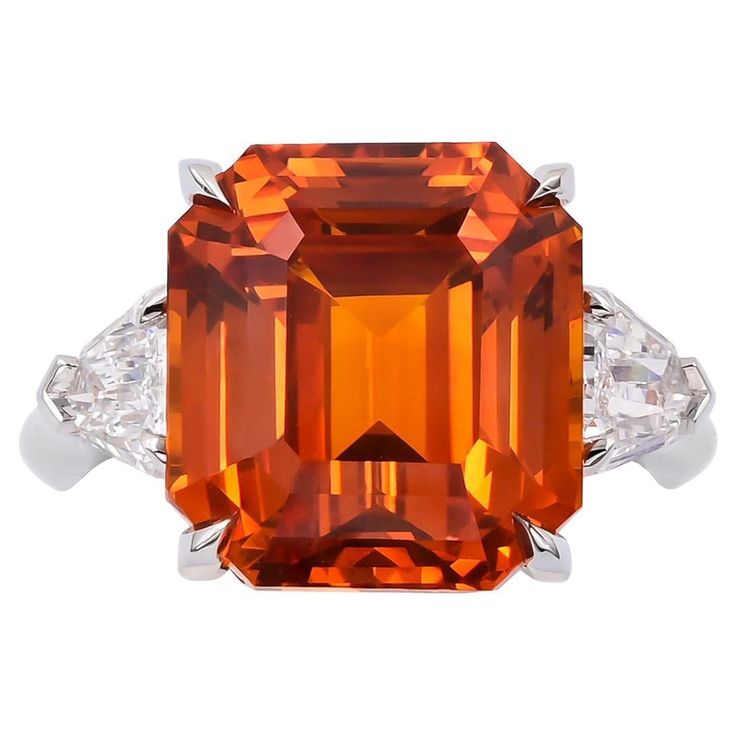 This breathtaking Cocktail Ring feature a magnificent emerald-cut orange sapphire at its center. Weighing an impressive 13.06 carats, this gemstone commands attention with its vivid hue and remarkable clarity. Certified by the prestigious Gemological Institute of America (GIA), the sapphire bears testament to its quality, having undergone heating and clarity enhancement processes to enhance its natural beauty. While its origin remains unknown, its allure is undeniable, making it a coveted additi Orange Sapphire Ring, Purple Sapphire Ring, Cut Orange, Contemporary Ring, Orange Sapphire, Expensive Jewelry, Sapphire Diamond Ring, Modern Ring, Tiffany And Co