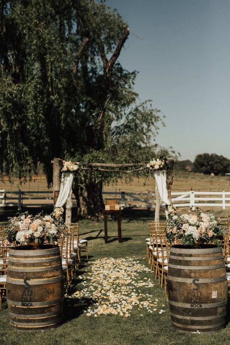 an outdoor ceremony setup with wooden barrels and flowers