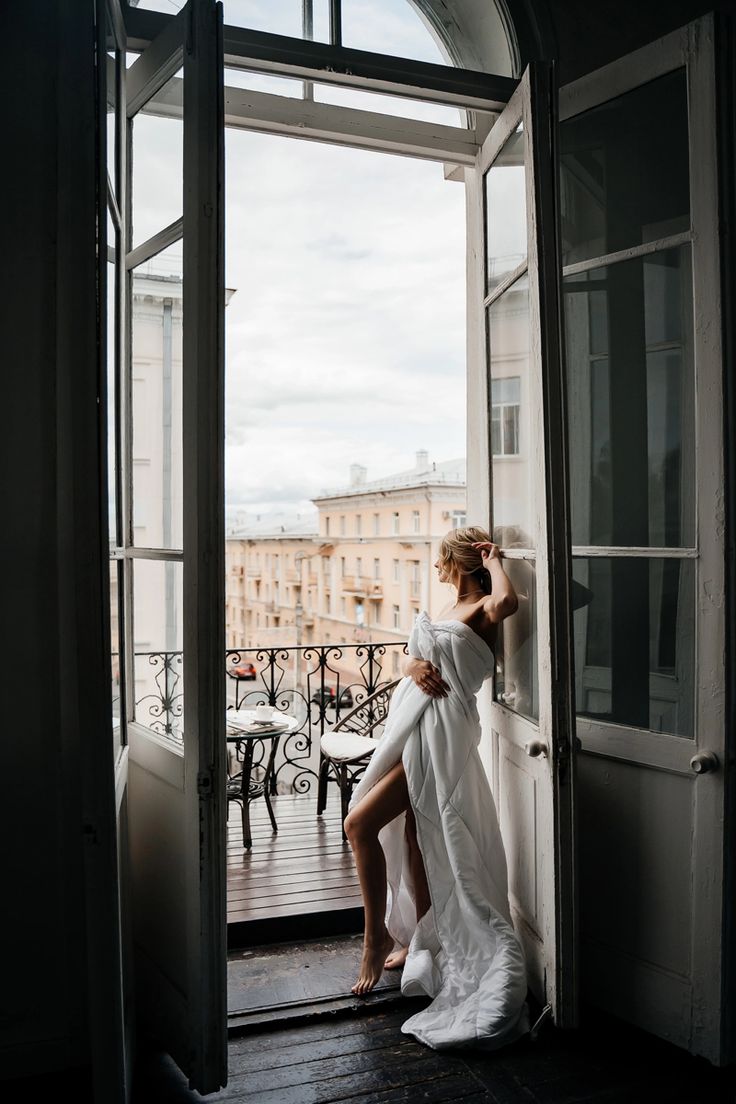 a woman in a white dress leaning against a door