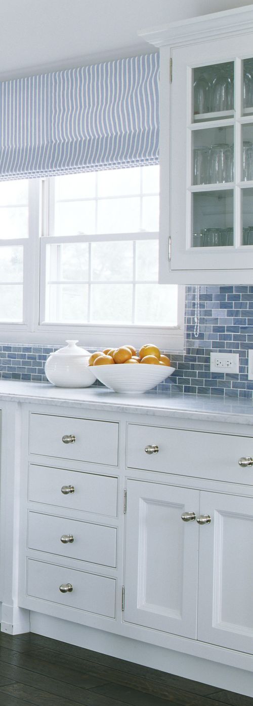 a kitchen with white cabinets and blue glass tile backsplash, counter tops and drawers