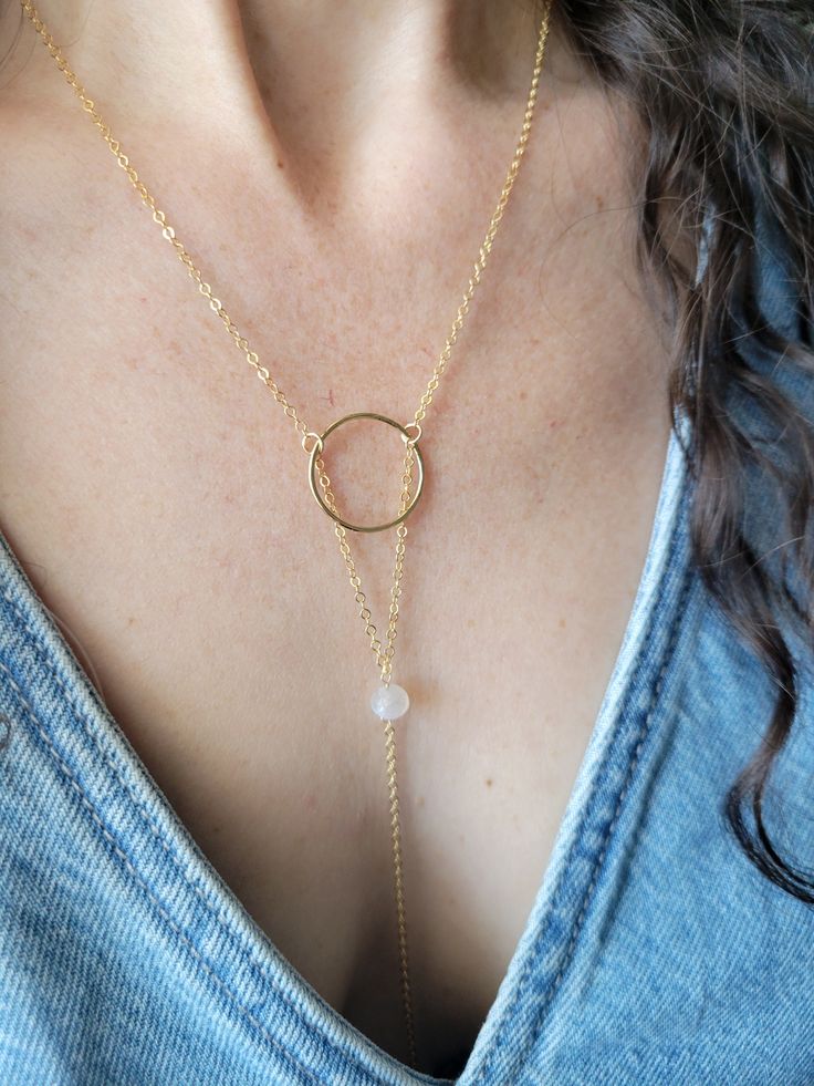 The Moon Beam Necklace features a beautiful petite Moonstone Gem. It is a lariat style necklace and is dainty and feminine! You can wear it so it is tucked into your top like shown or worn out. The circle is hammered and the length of the drop from the top of the circle down to the bottom on the chain is about 5 in. The length shown in the pictures is at a 16 in chain length. Each piece is handmade and may vary slightly as well as the stones as they are natural. Thank you! Adjustable Dainty Lariat Necklace For Layering, Adjustable Delicate Chain Lariat Necklace, Adjustable Dainty Round Lariat Necklace, Adjustable Round Lariat Necklace In Dainty Style, Adjustable Round Lariat Necklace With Delicate Chain, Dainty Circle Adjustable Necklace, Adjustable Round Minimalist Lariat Necklace, Adjustable Minimalist Lariat Necklace, Dainty Round Lariat Necklace With Delicate Chain