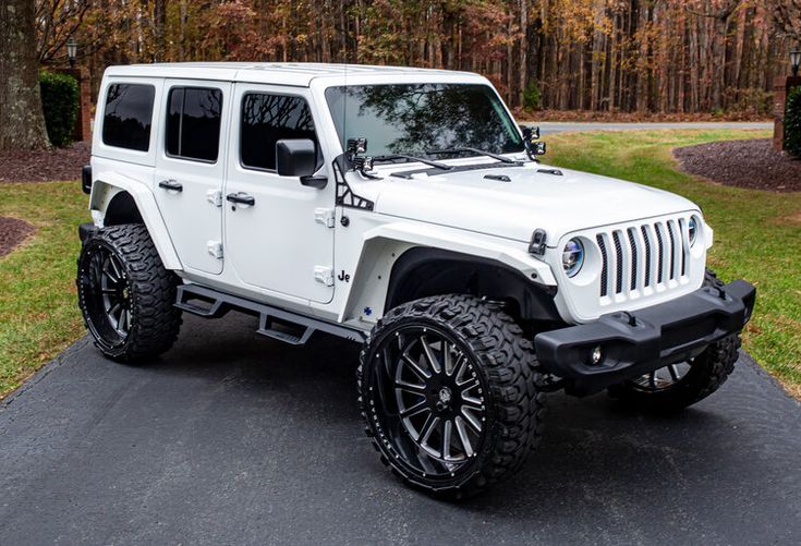 a white jeep is parked in front of some trees