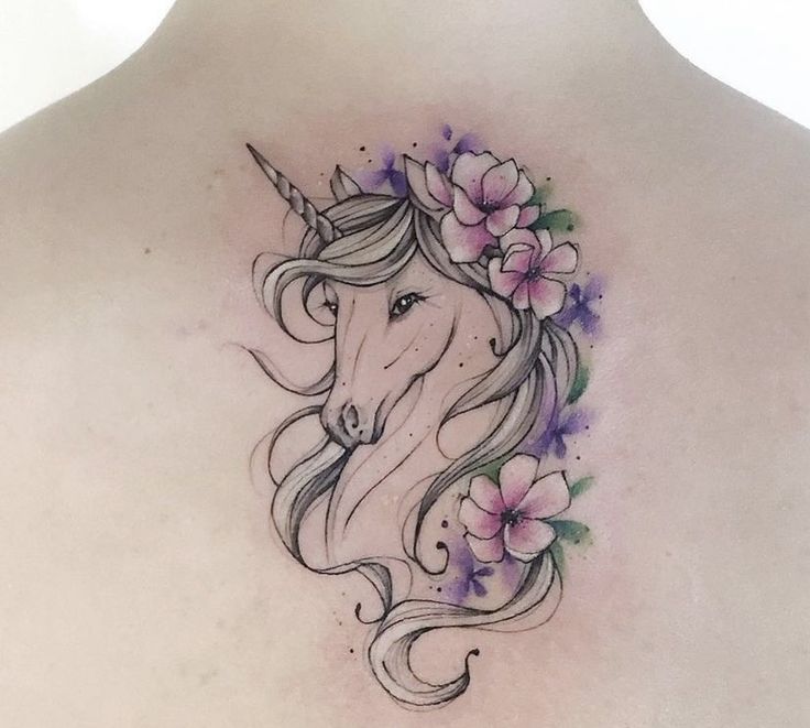 the back of a woman's shoulder with a unicorn and flowers tattoo on it