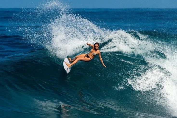 a woman riding a wave on top of a surfboard