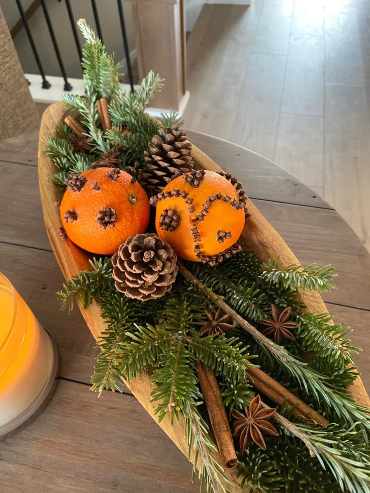 a wooden boat filled with pine cones and oranges on top of a wood table